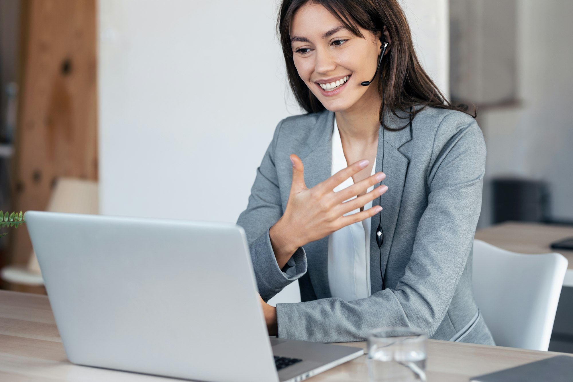 young business woman making video call with computer while talking with earphone sitting in office.